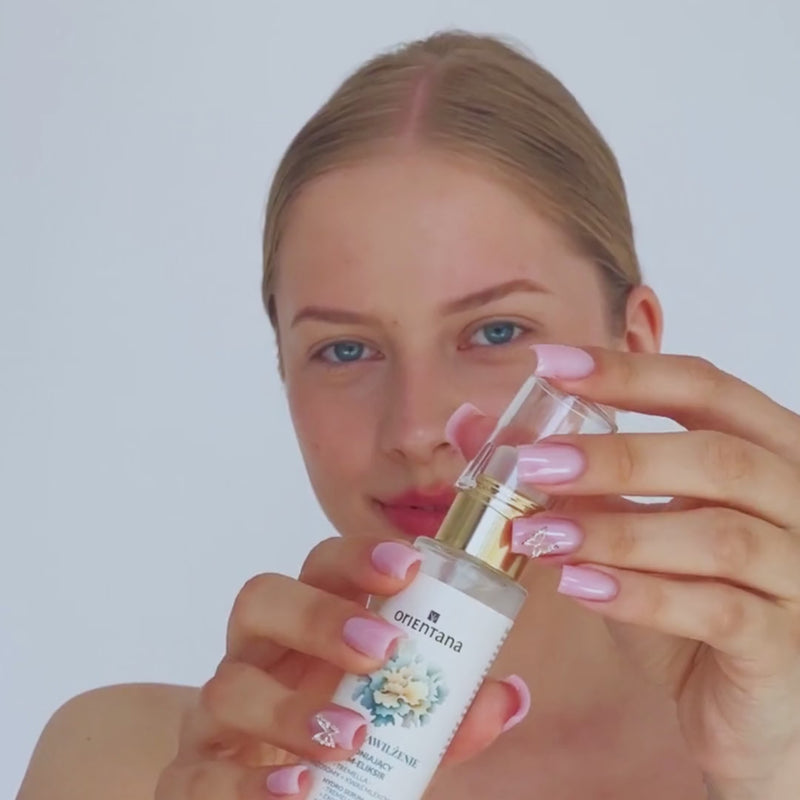 Video z widoczną modelką, która otwiera serum eliksir, naciska pompkę i pokazuje piękną, lekką konsystencję produktu. Na końcu widać twarz modelki w dziennym świetle - skóra ma naturalny glow i widocznie jest nawilżona.